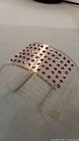 Oblique view of clear lucite cuff showing pink rhinestones on exterior