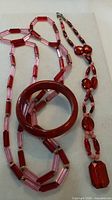 Overview of two necklaces and red bangle bracelet