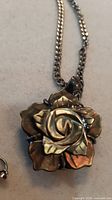 Front view close-up of carved shell rosette pendant on chain