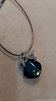 front view of deep blue crystal pendant on silver snake chain