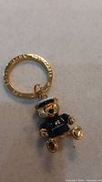 Front view of gold-tone engraved key ring and teddy bear charm