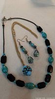 All jewellery pieces laid out: beaded necklace, chain pendant, earrings