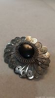 Front view showing black cabochon and filigree petals