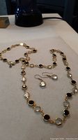 Necklace laid out showing alternating black and clear stones with matching earrings