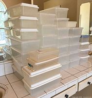 Stacked clear plastic shoe boxes with lids on countertop
