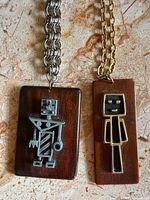 close-up of two wood pendants with metal figure inlays on chains