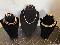 All three necklace and earring sets displayed on stands