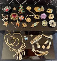 All vintage costume jewelry pieces laid out showing brooches, necklace, bracelet, earrings and pendant