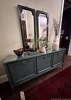 Front angled view of painted credenza with two mirrors and accessories
