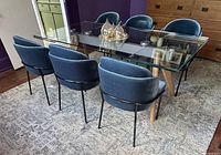 Six blue velvet Angelo chairs around glass dining table