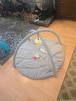 Overall view of grey round baby play gym mat with arches and toys