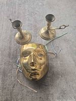 All three items: two brass candlesticks and brass mask