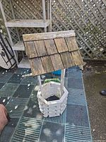 Front view of wooden wishing well showing lattice base and shingled roof