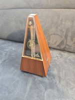 Side view of woodgrain pyramid metronome with clear cover