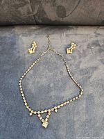 Necklace fully laid out with earrings above for scale and design overview