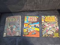 Three Star Wars comics laid out on sofa: Return of the Jedi (left), two Star Wars Weekly issues (centre, right)