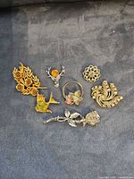 All seven brooches arranged on dark surface