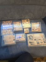 Eight clear plastic cases of assorted wood-mounted rubber stamps displayed on sofa