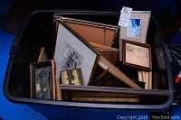 Overview of plastic bin filled with assorted framed artworks and frames