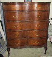 Full view of wooden serpentine highboy dresser with seven drawers