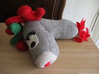 Stuffed grey knit sock showing reindeer head with felt antlers, eyes, mouth, holly leaves