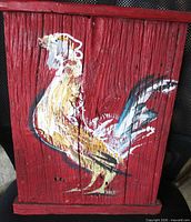 Front view of rooster painting on red wooden board