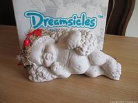 Front view of Dreamscicles sleeping cherub in front of original box