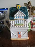 Front view of ceramic Old Sweet Shop teapot showing building shape, spout, handle and painted details