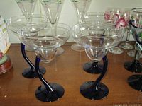 Four clear margarita glasses with cobalt curved stems and bases on tabletop