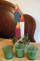 Three pillar wooden candle art with three green glass votives in front
