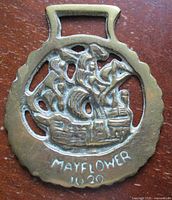 Front view of brass ornament showing ship motif and inscription