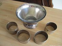 Silver-plated bowl and four napkin rings displayed on tabletop