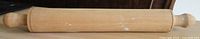 Full view of wooden rolling pin showing handles and wear