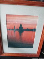 Front view of framed photograph showing sailboats at sunset within mat and wood frame