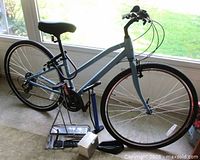 Full view of Raleigh light blue hybrid bicycle and accessories on floor