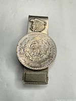Front view of money clip showing mounted 1 Peso coin and clip body