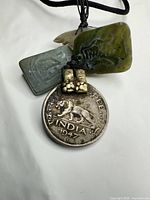 Front view of coin with tiger, green and grey carved stone charms, brass spacers