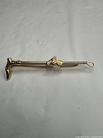 Full view of gold-tone equestrian tie clip showing horse head and hoof ends