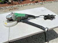 Full view of angle grinder with dust shroud and hose on table