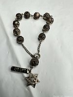 Full bracelet laid flat showing rose beads, chain, clasp, two charms