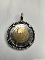 Obverse view of pendant showing female bust side of 500 Lire coin within sterling bezel