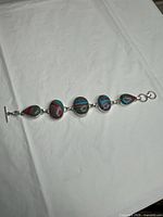 Full view of sterling silver bracelet showing five Fordite cabochons and toggle clasp