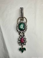 Full view of sterling silver money clip showing clip arm, central emerald cabochon cluster, hanging drop with pink and green cabochons