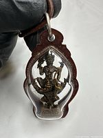 Front view of bronze deity amulet inside brown resin case