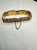 Full view of gold plated rectangular-link bracelet with safety chain