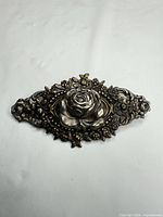 Front view of silver-tone rose brooch showing overall design