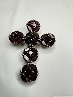Front view of sterling silver cross pendant with deep red garnets