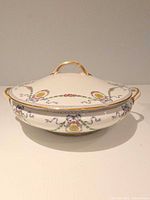 Full view of covered tureen showing decoration and gold-trimmed handles