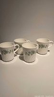 Four CorningWare mugs displayed upright showing ivy pattern
