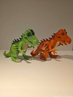 Green and orange plastic T-Rex figures side by side